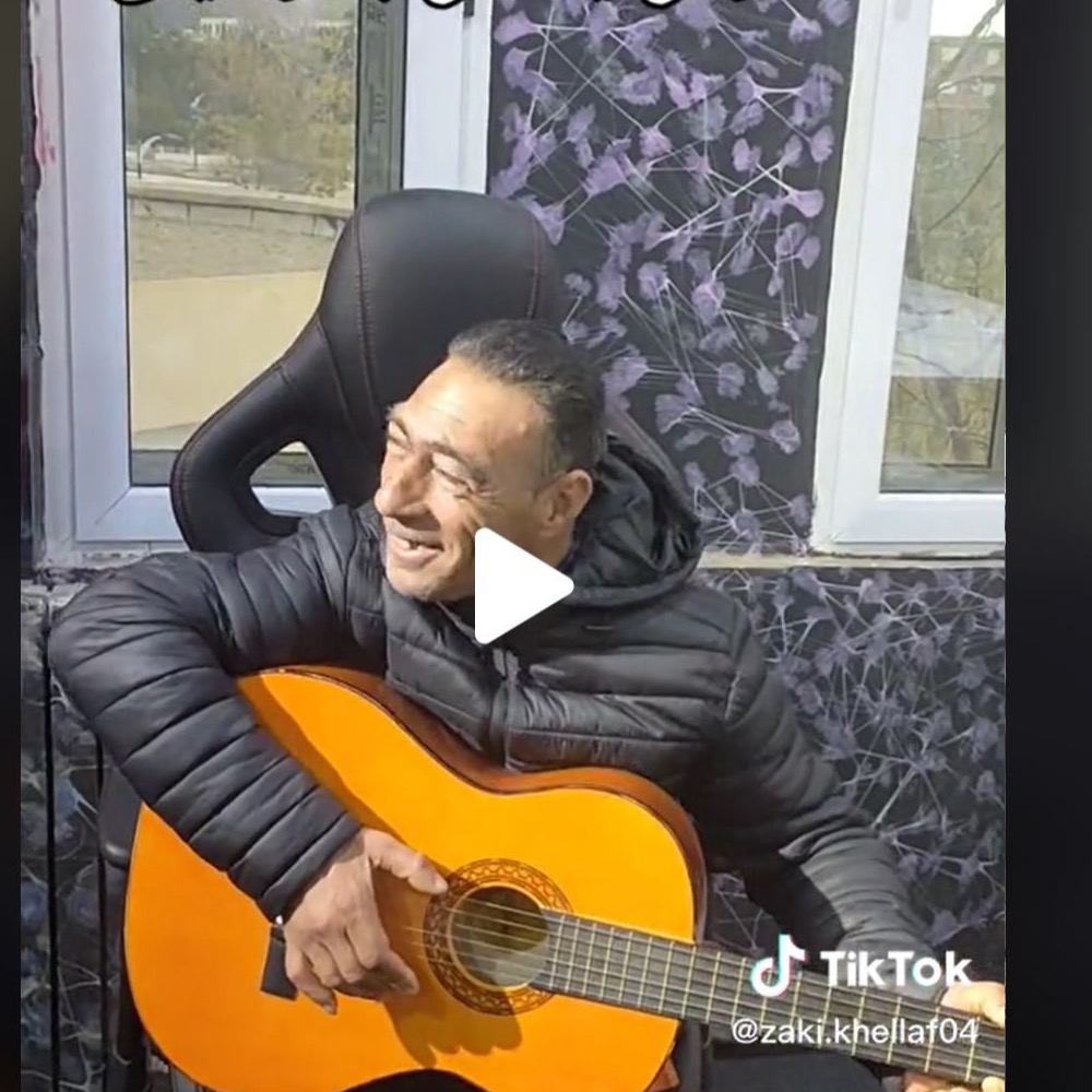 Choucha playing an acoustic guitar and laughing